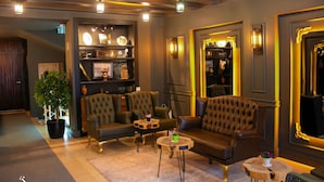 A modern lounge area with leather sofas, a coffee table, and a bookshelf. - Hotel Zade (Erzurum)
