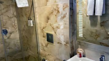 Un bagno moderno con rivestimento in marmo, box doccia in vetro e lavabo con specchio.
