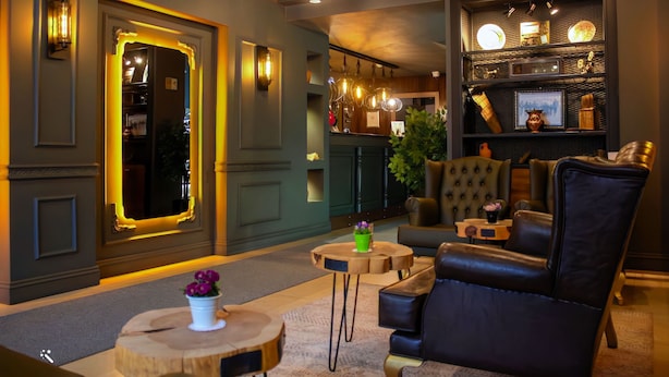 A modern lounge area with leather seating, a round wooden table, and decorative lighting. - Hotel Zade (Erzurum)