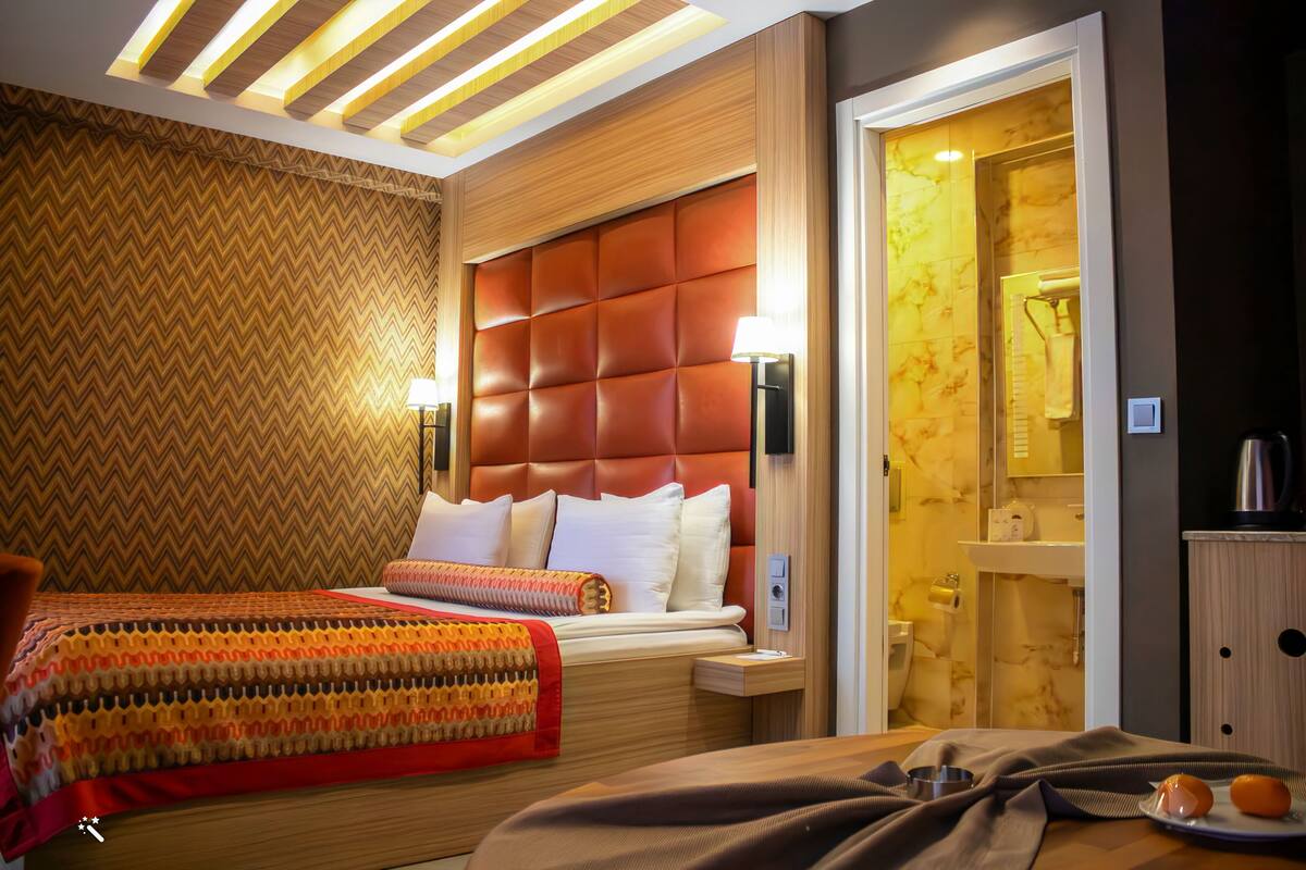 A hotel room with two beds, a large padded headboard, a mirror, and a bathroom visible through an open door.