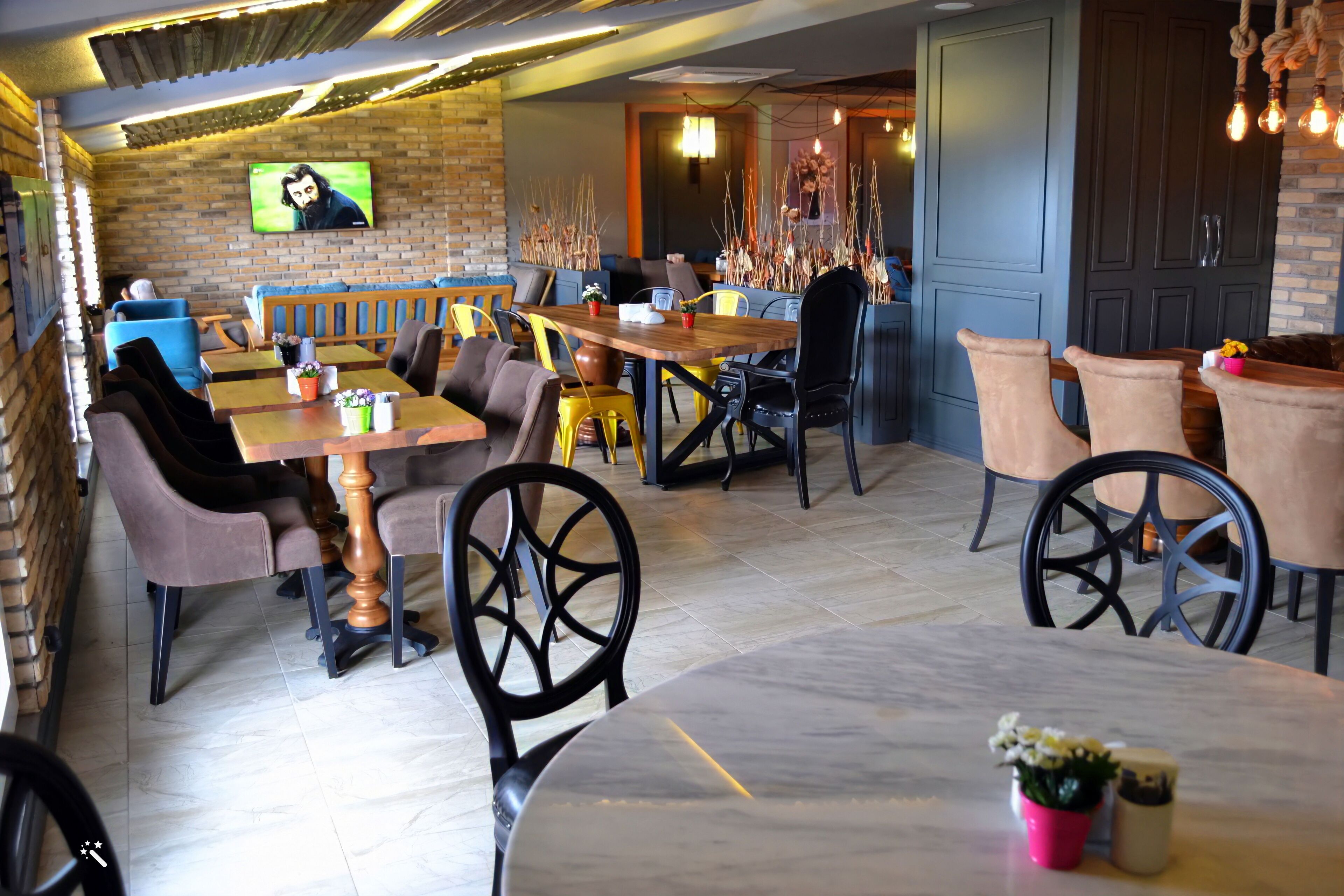 A restaurant with brick walls, wooden tables, and various seating arrangements including booths and chairs.