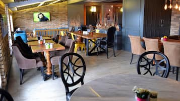 Un restaurante con paredes de ladrillo, mesas de madera y diferentes opciones de asientos, incluyendo cabinas y sillas.