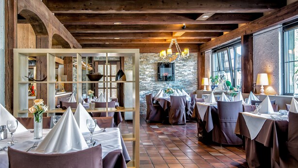 A restaurant with wooden beams, stone walls, and tables set for dining. - Hotel Restaurant Schwyzerhuesli (Viernheim)