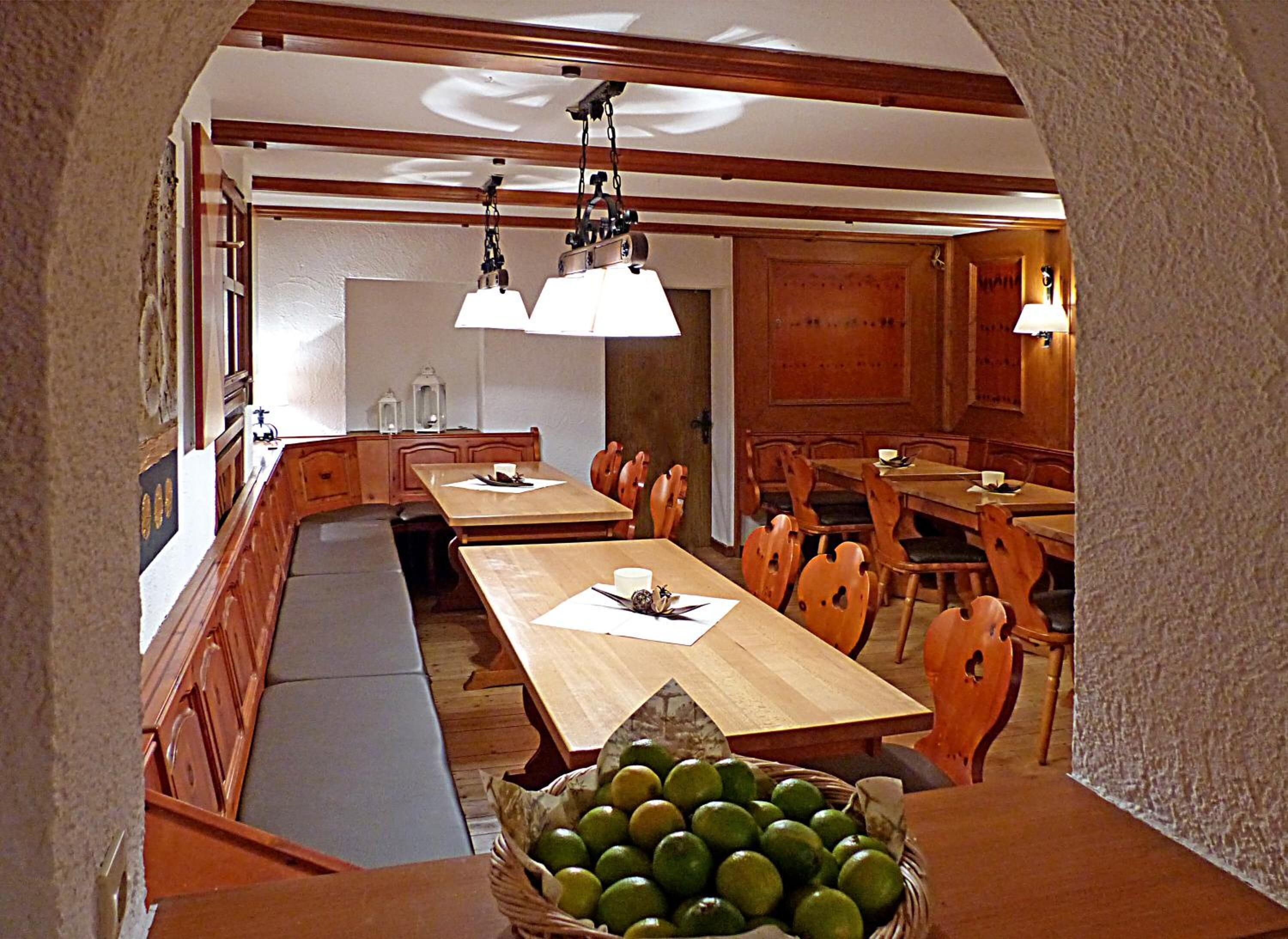 Un comedor con una mesa de madera larga, varias sillas y un banco. Hay una cesta de limones sobre la mesa.