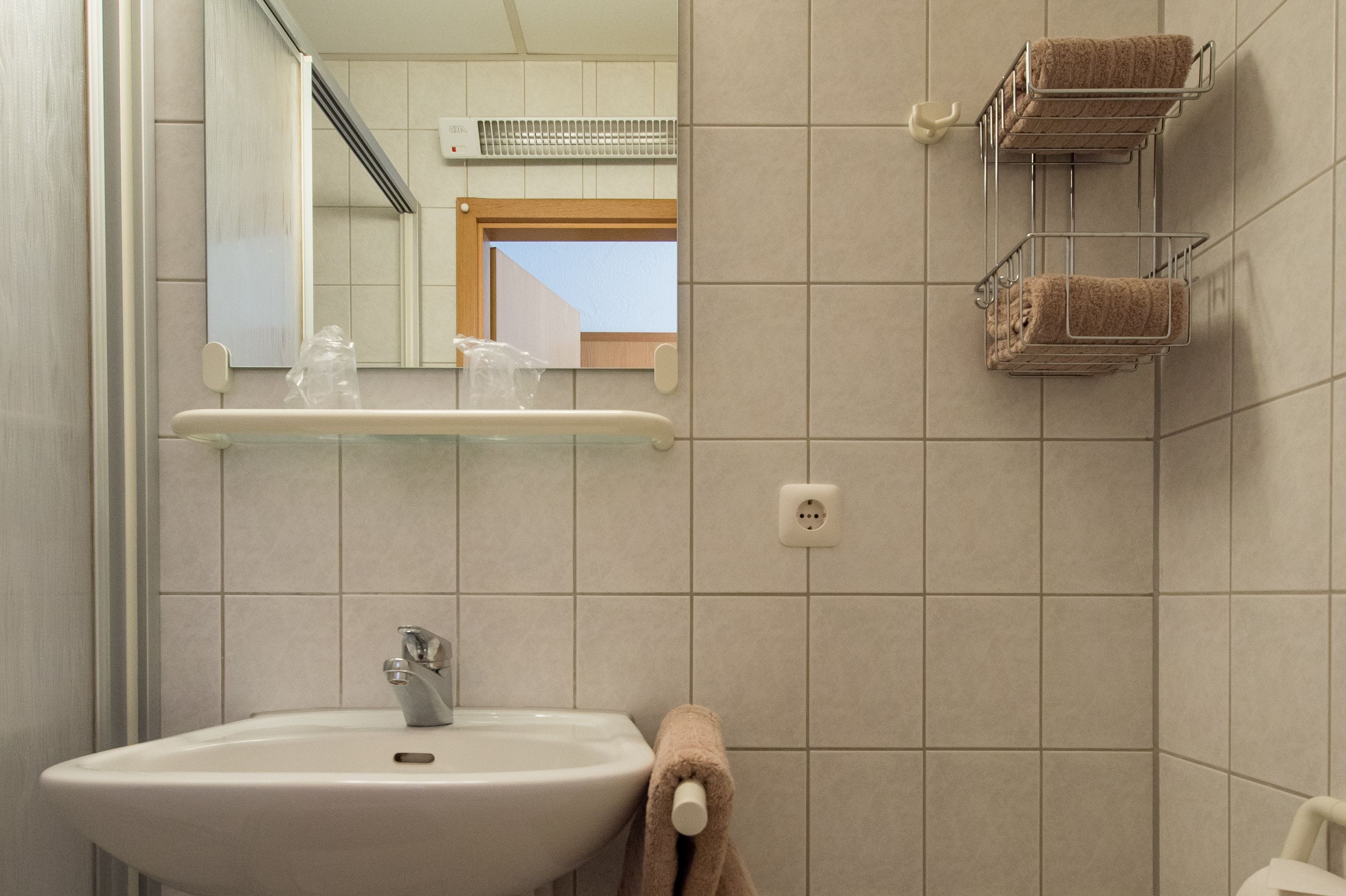 A bathroom with a sink, mirror, towel rack, and a window.