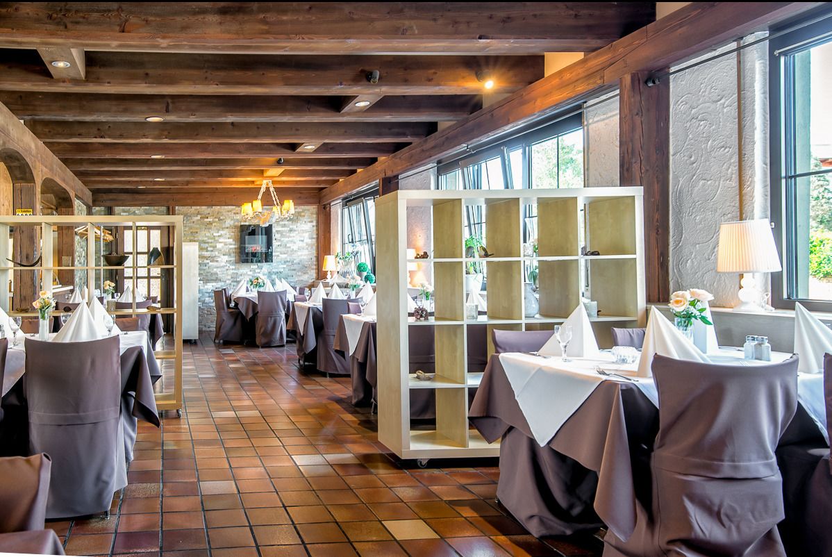 A restaurant with wooden beams, tiled floors, and tables set for dining.