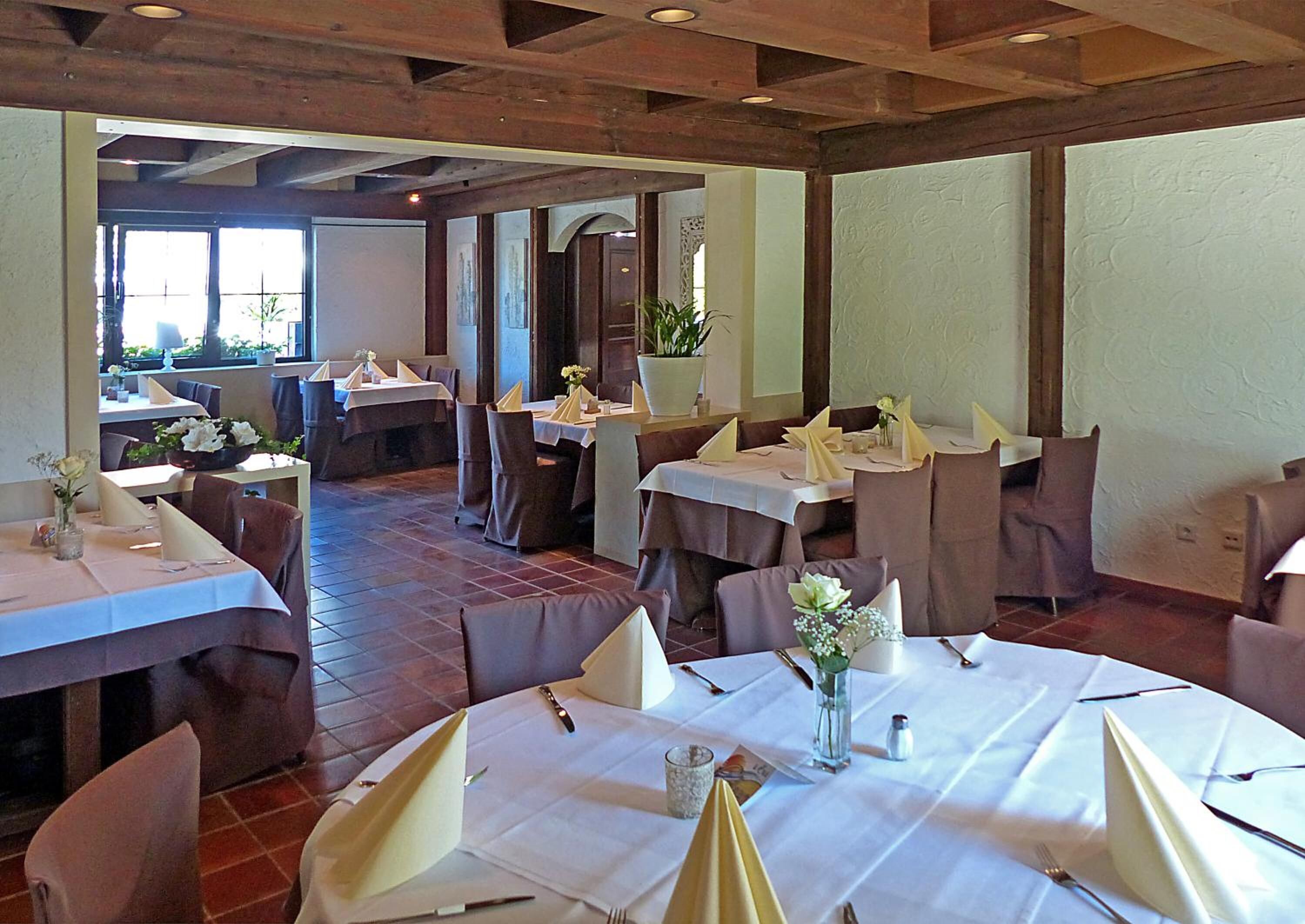 A restaurant with multiple tables set for dining, featuring white tablecloths and neatly arranged napkins.
