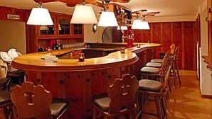 A bar area with wooden chairs, a bar counter, and ceiling fans. - Hotel Restaurant Schwyzerhuesli (Viernheim)