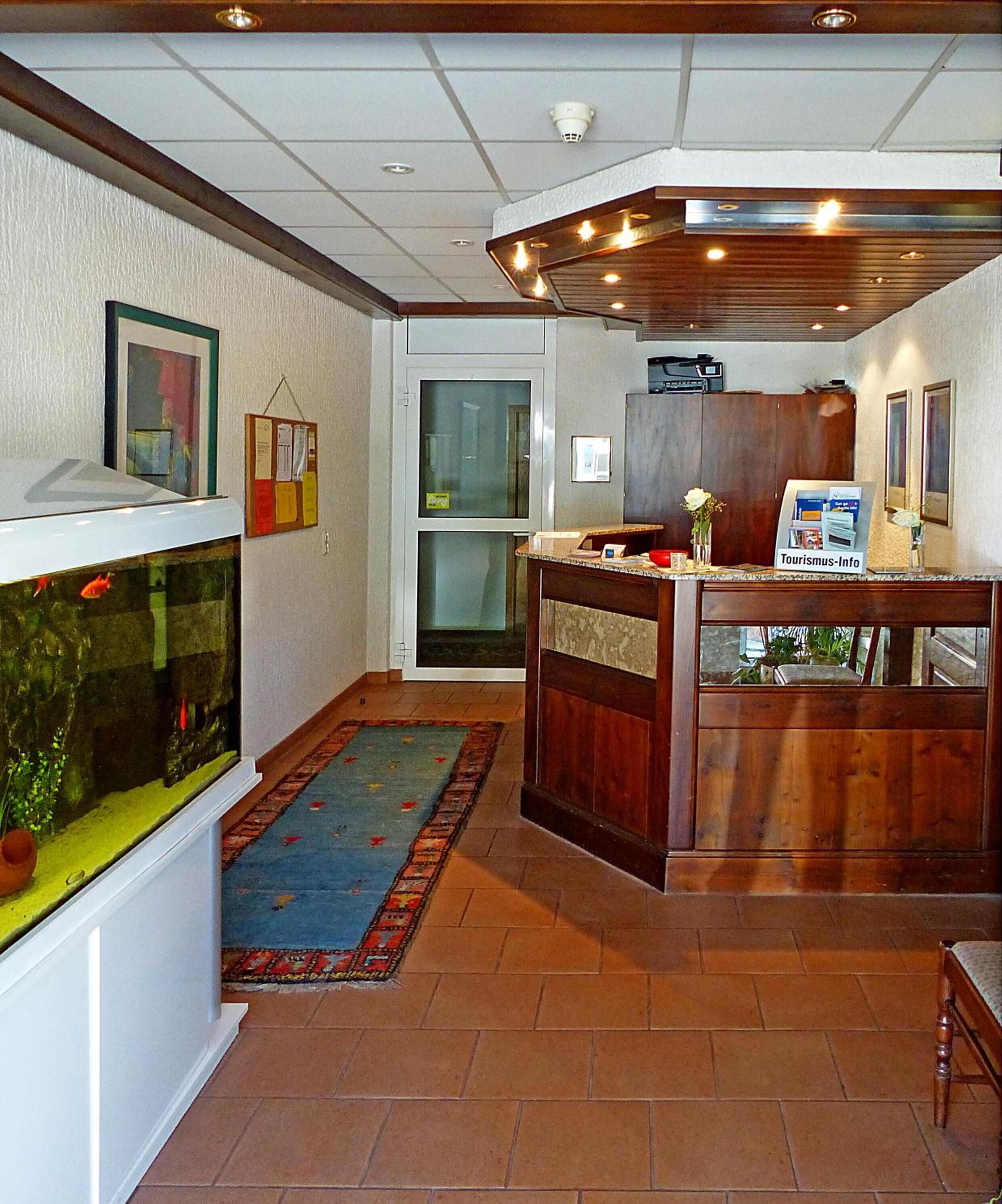Ett välkomstområde med ett akvarium, en receptionsdisk i trä och en anslagstavla.