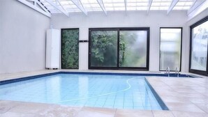 Una piscina interior con suelo de baldosas y techo de cristal.