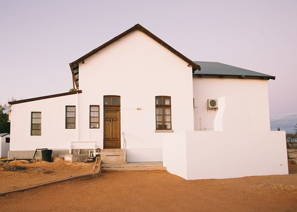 A white building with a gabled roof, a front door, and a small porch area.