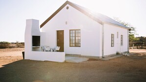 Un edificio blanco con chimenea, una puerta y una ventana.