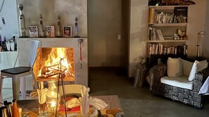 A cozy living room with a fireplace, a bookshelf, and a comfortable seating area.