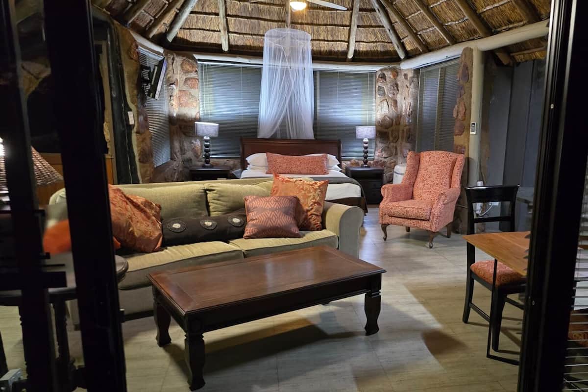 A room with a bed, a sofa, a chair, and a table.