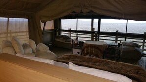Un chalet confortable avec un lit, un canapé et une petite table. Il y a une fenêtre donnant sur l’océan.