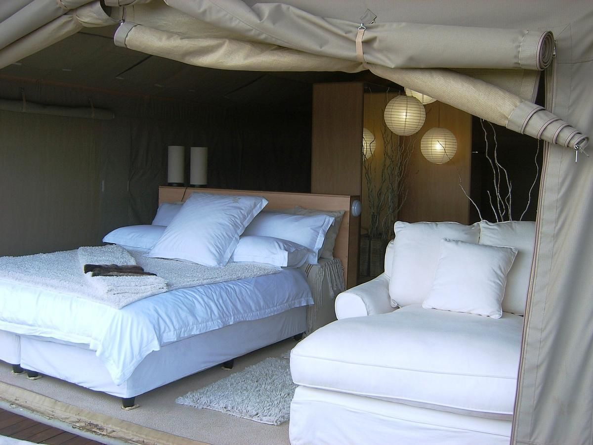 A bedroom with two beds, a sofa, and a canopy.