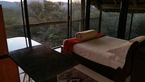 Une chambre à coucher avec un lit, une fenêtre et une vue sur les arbres.