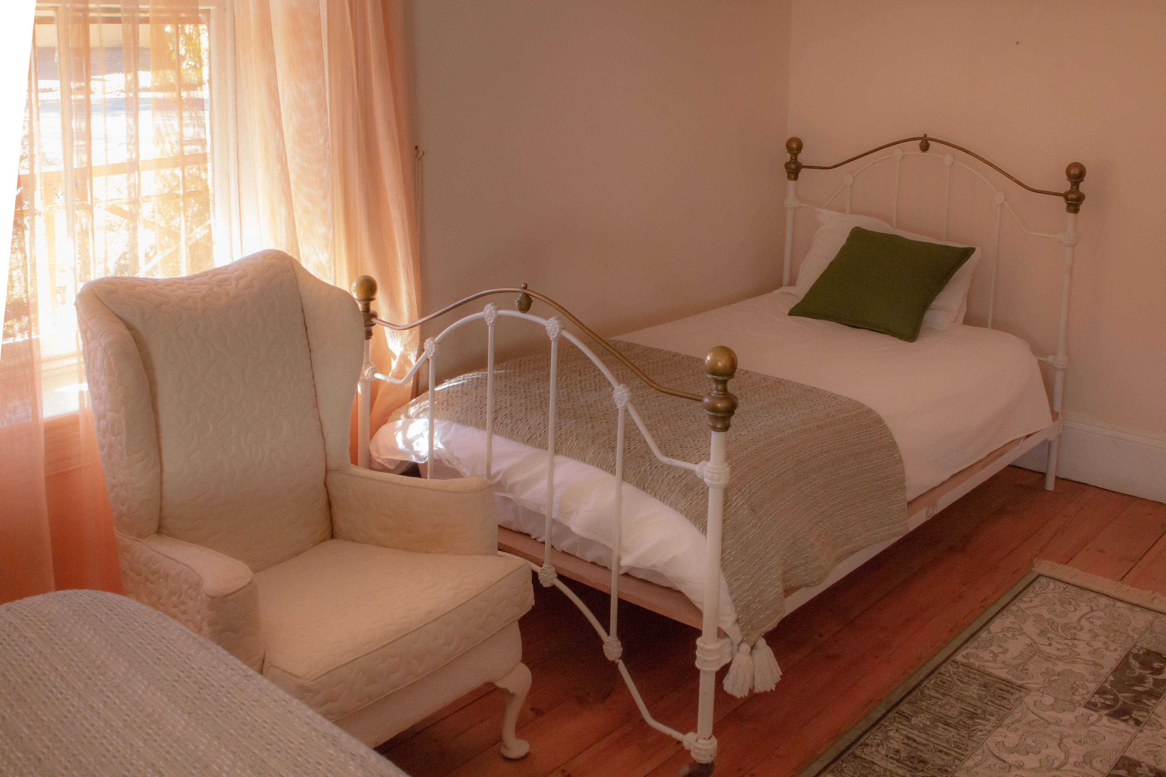 A bedroom with a single bed, a chair, and a nightstand.