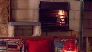Une pièce chaleureuse avec un mur en pierre, une cheminée et une table sur laquelle est posée une lanterne.