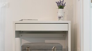 Un escritorio blanco con una maleta gris debajo.