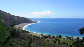 Paisaje costero con playa, océano y terreno montañoso.