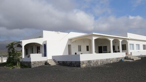 Un edificio blanco con techo plano y varias ventanas arqueadas.