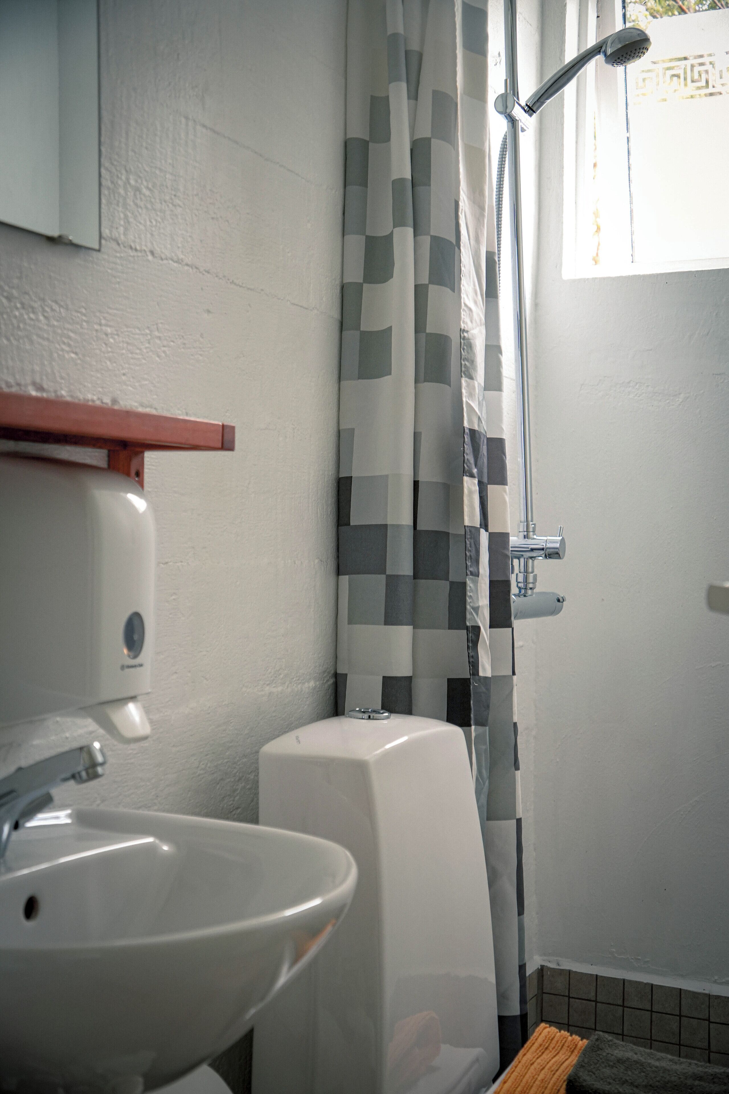 Ein Badezimmer mit Waschbecken, Toilette und Dusche mit kariertem Vorhang.