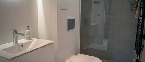 Une salle de bain moderne avec un lavabo blanc, des toilettes et une douche à parois de verre.