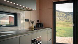 A modern kitchen with a large window, a built-in oven, and a view of a mountainous landscape. - Stóra Mörk Guesthouse (Rangárþing eystra)