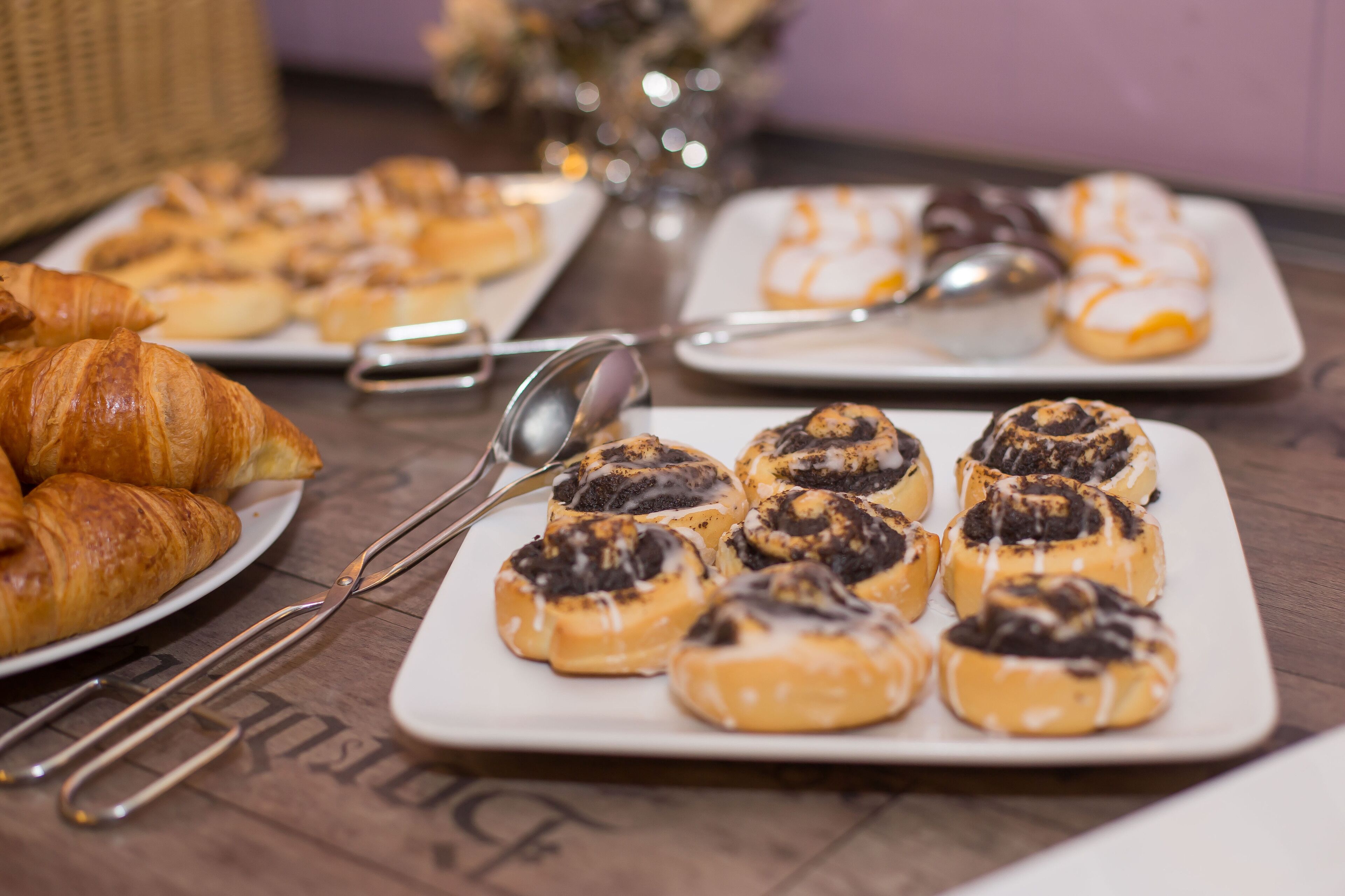 Una mesa con pasteles y cruasanes, una cuchara y un tenedor.