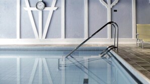 Una piscina con una escalera de metal y un reloj en la pared.