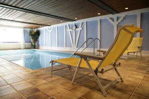 Zona de piscina con una silla de descanso amarilla, una planta en maceta y vistas a la piscina.