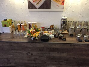 Una mesa de buffet con diversos alimentos, salsas y bebidas.