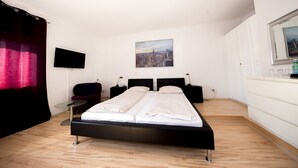 Una habitación de hotel con cama, televisión, un cuadro, escritorio y ventana.