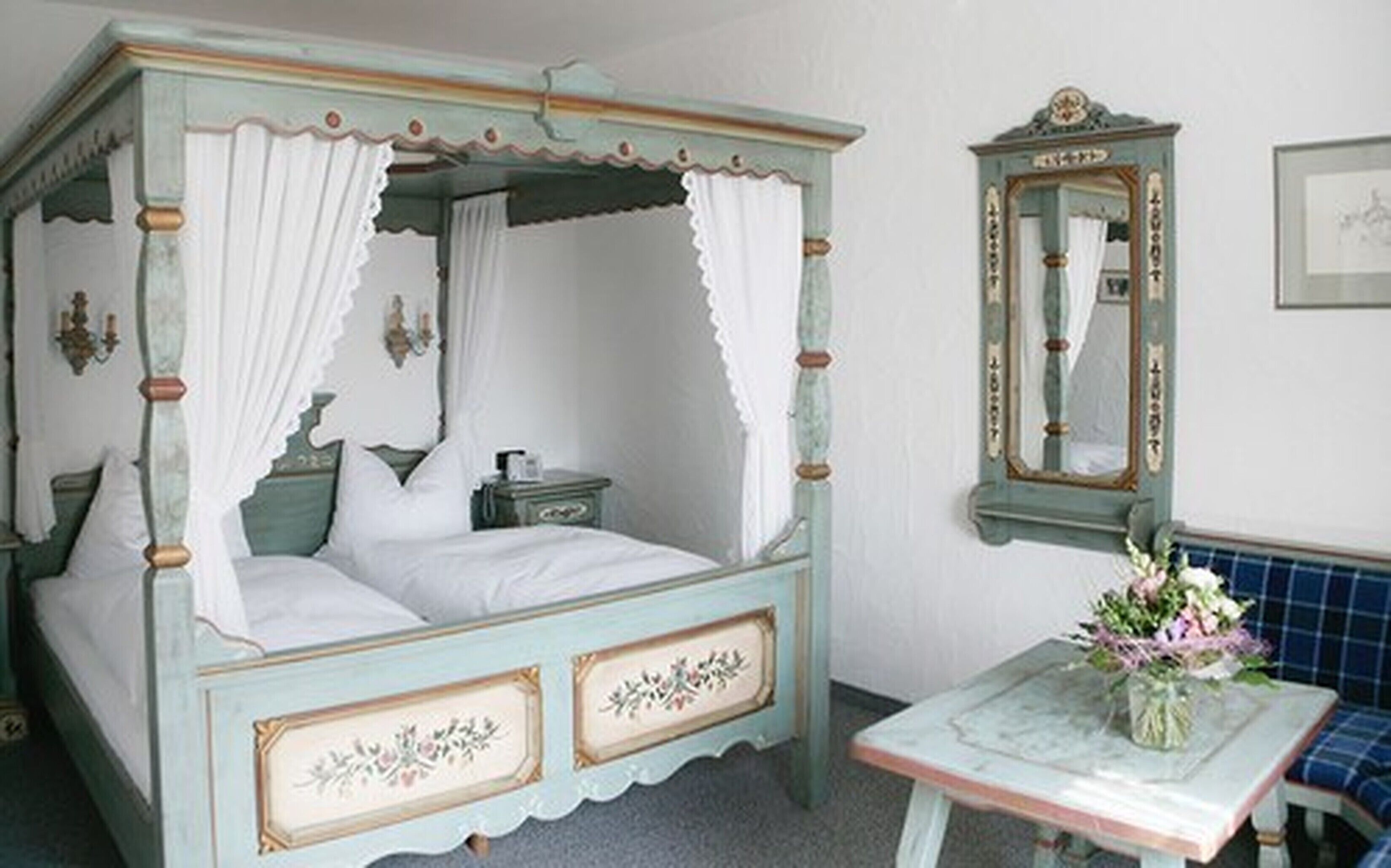 A four-poster canopy bed with a nightstand and a mirror.