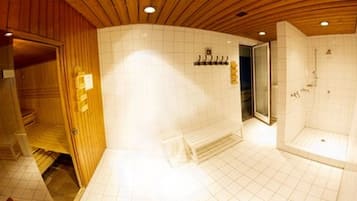 Un baño moderno con techo de madera, zona de ducha y suelo de baldosas.
