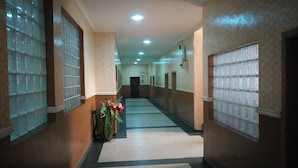 A corridor with patterned walls, a tiled floor, and multiple doors along the walls. - Mataan Hotel  Suites (Ibadan)