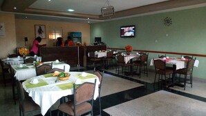 A restaurant with multiple tables, chairs, and a TV mounted on the wall. - Mataan Hotel  Suites (Ibadan)