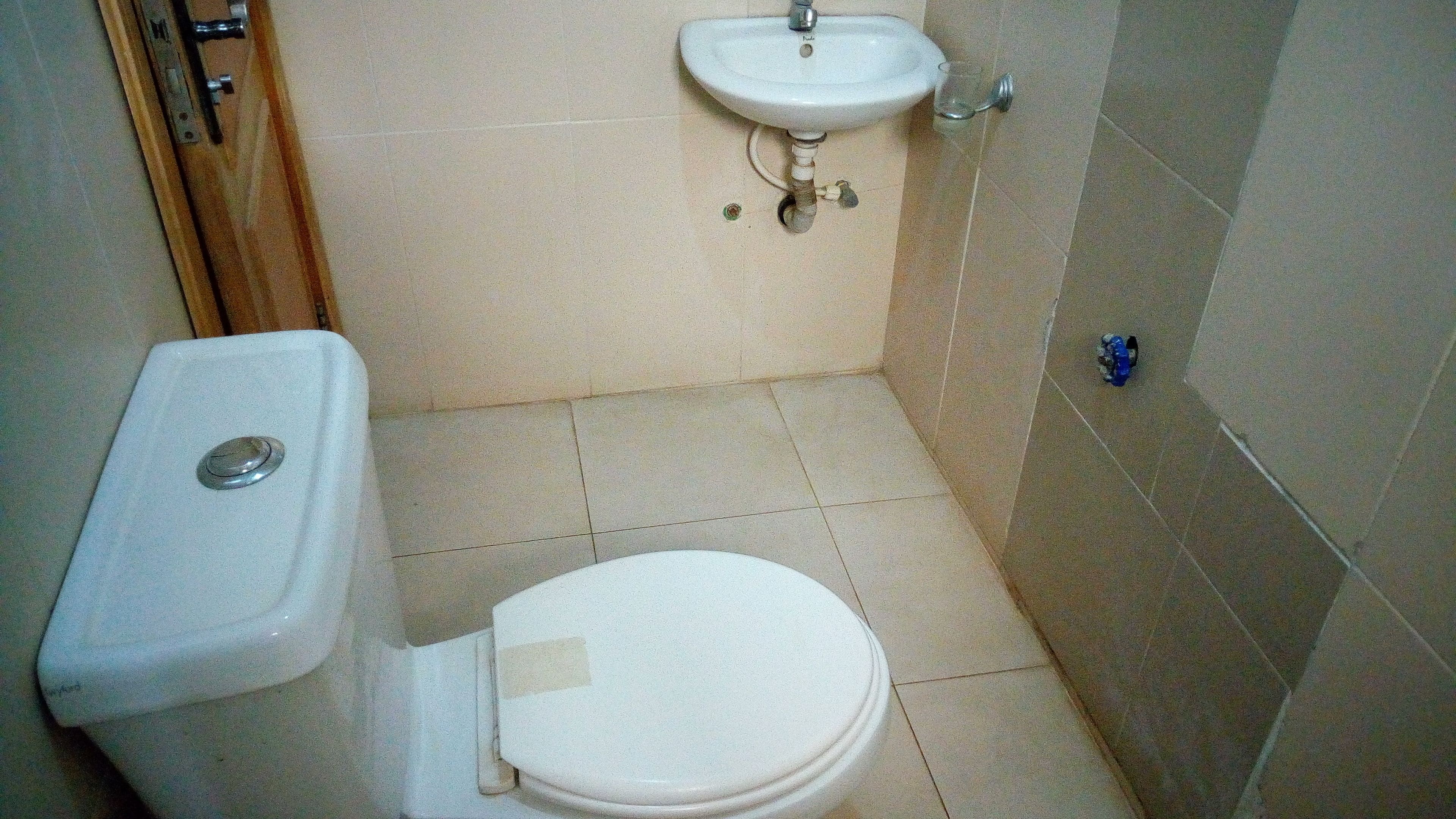 A small bathroom with a toilet, sink, and tiled floor.