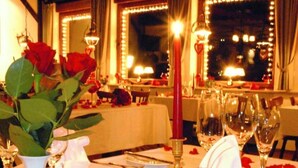 Une table à manger décorée de roses rouges, de bougies et de verres à vin, créant une ambiance romantique.