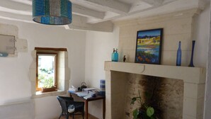 A room with a fireplace, a painting above it, a window, and a desk with a chair. - Chambres d'hôtes Au BO Voyage (Tavant)