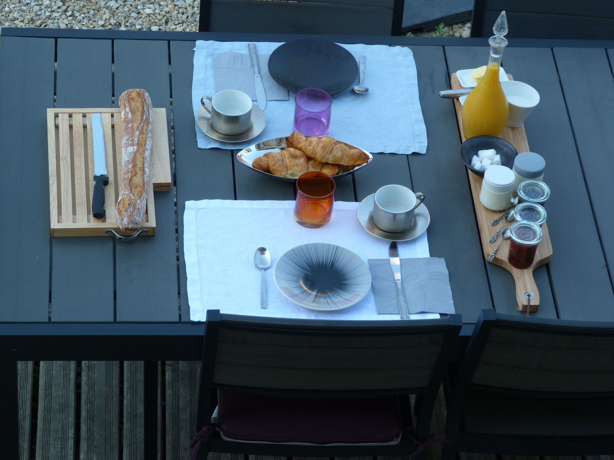 Una mesa de desayuno con croissants, pan y diferentes salsas.