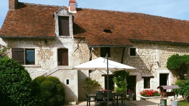 A stone building with a tiled roof, outdoor seating, and a gravel courtyard. - Chambres d'hôtes Au BO Voyage (Tavant)