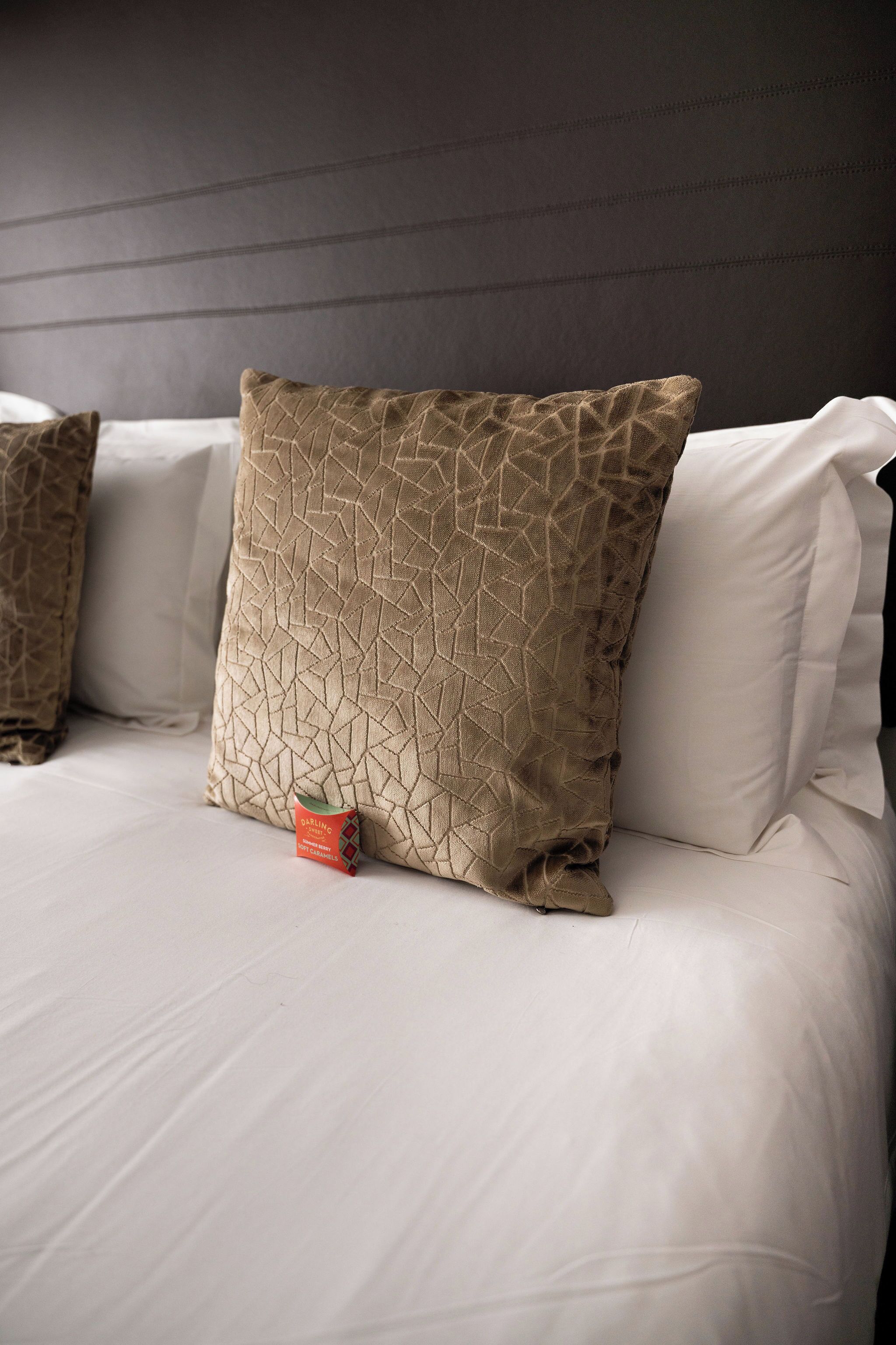 A bed with white linens and two patterned pillows.