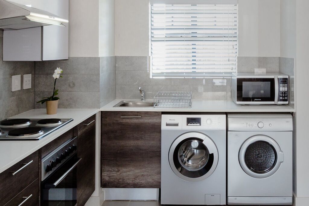 A modern kitchen with a built-in oven, microwave, and two washing machines.