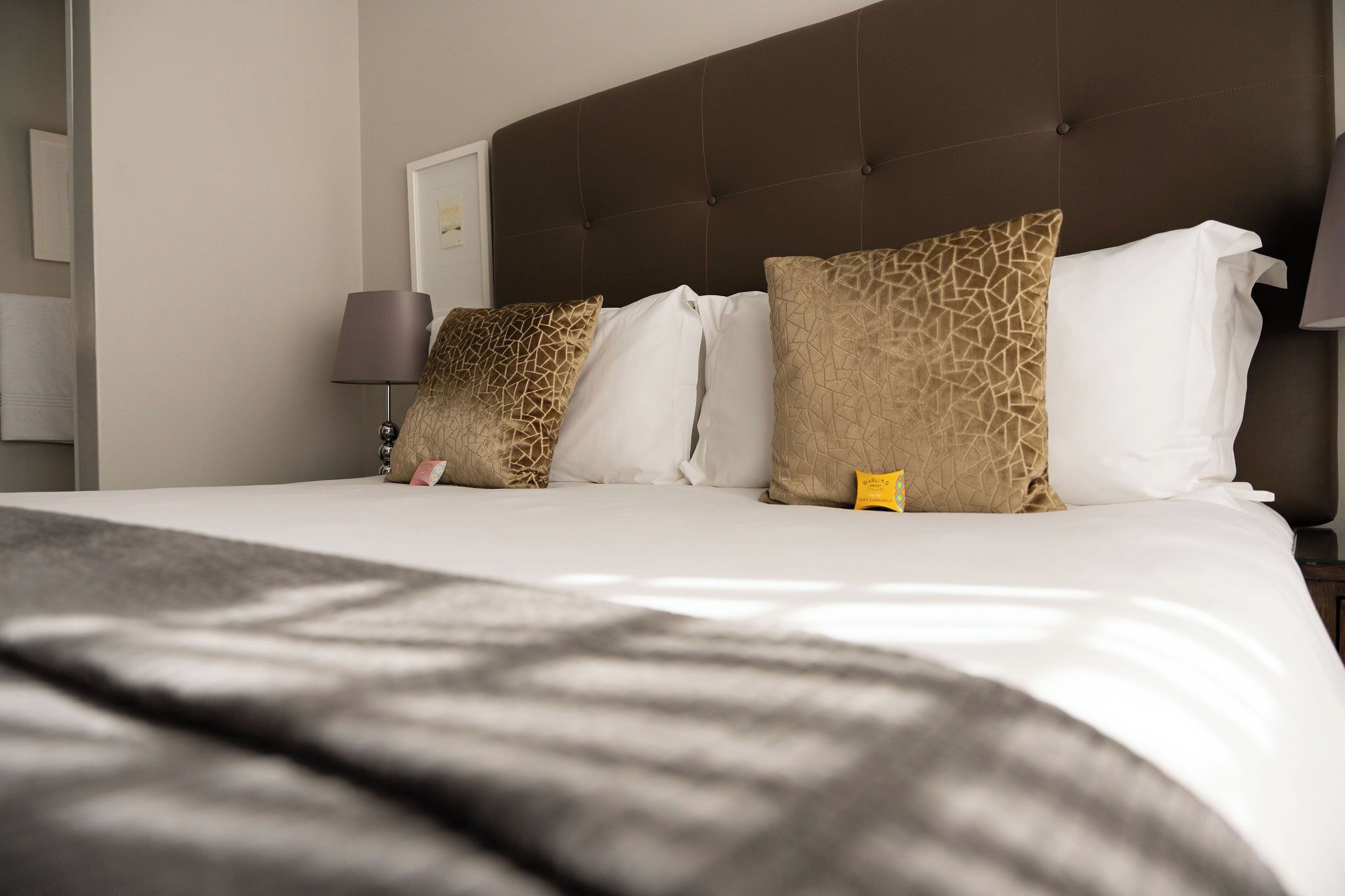 A hotel room with a large bed, a headboard, and a nightstand with a lamp.
