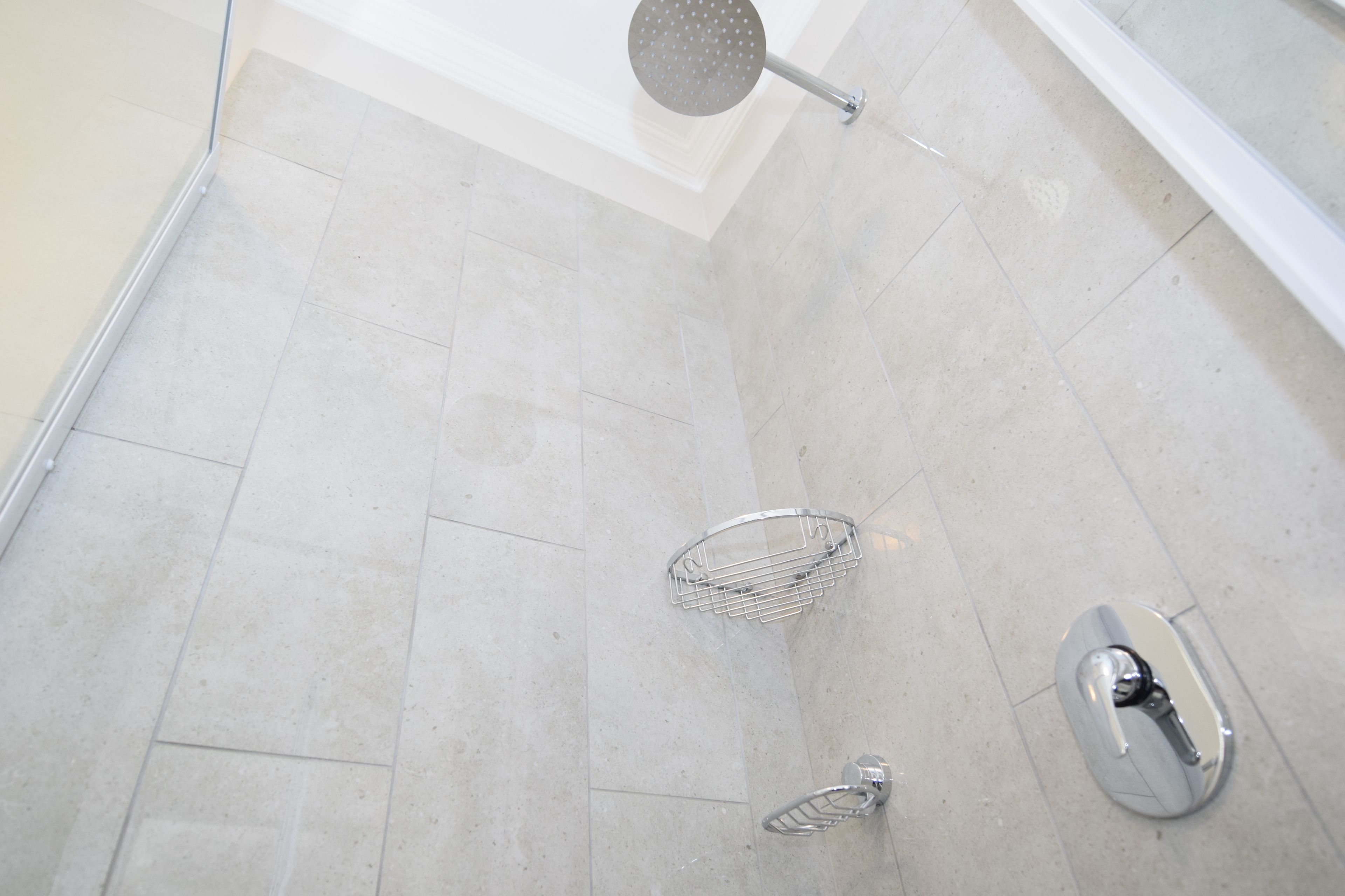 A modern shower area with a handheld showerhead, a handheld shower head, and a shower caddy.