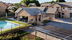 Edificio residencial con piscina, paneles solares y césped cuidado.