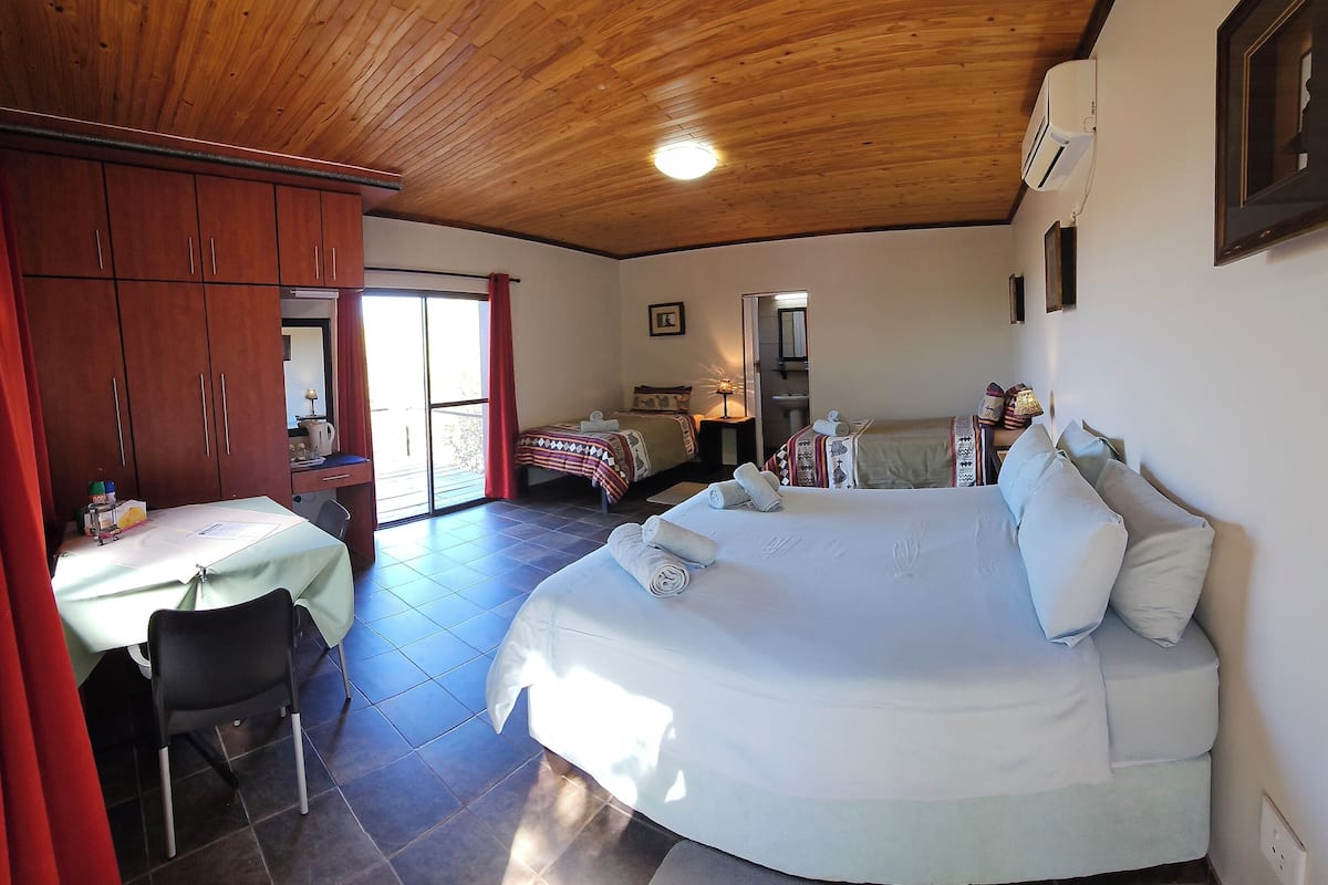 Un dormitorio con una cama grande, un escritorio con silla y un armario.