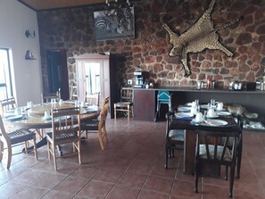 Ein Restaurant mit Steinwänden, einer Zebra-Zeichnung und einer Leopard-Dekoration. Die Tische sind mit Tellern, Gläsern und Besteck gedeckt.